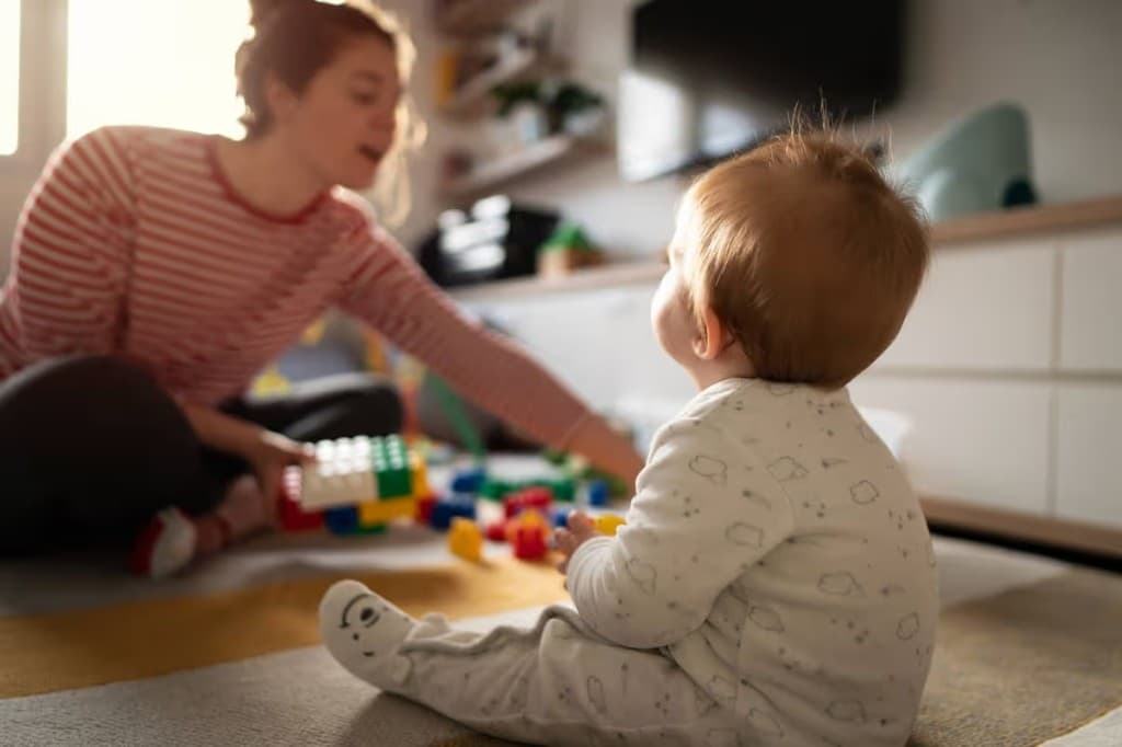 A toddler and caregiver playing with colorful building blocks during an in-home pediatric speech therapy session
